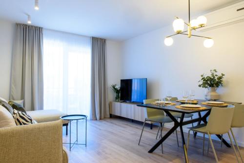 comedor y sala de estar con mesa y sillas en Stiva Apartment - new apartment with free parking, 150m from the beach, en Kaštela