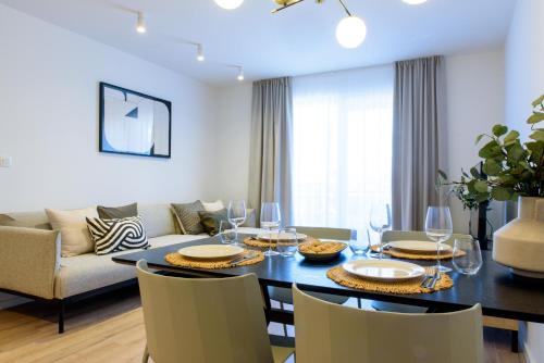 comedor con mesa, sillas y sofá en Stiva Apartment - new apartment with free parking, 150m from the beach, en Kaštela