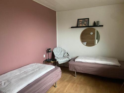 1 dormitorio con 2 camas, espejo y silla en Tornby Guesthouse, en Hirtshals