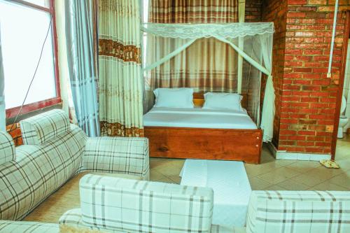 een kamer met een bed, 2 banken en een raam bij Heartland hotel in Kigali