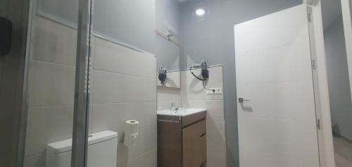 a white bathroom with a toilet and a sink at Apartamentos Las trece llaves Jacuzzi bajo reserva in Merida