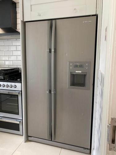 a stainless steel refrigerator in a kitchen next to a stove at River view Rooms in Rock Ferry