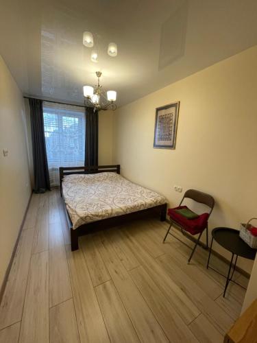 a bedroom with a bed and a chair and a window at LUXflats Rivne in Rivne