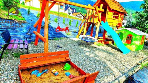 a playground with a bench and toys in the sand at Domki i pokoje Daglezja pod Górą Żar in Międzybrodzie Żywieckie