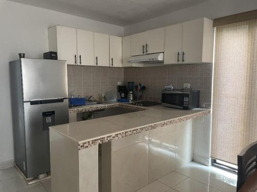 a kitchen with white cabinets and a stainless steel refrigerator at Casa Nora in Sisal