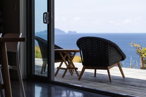 a chair sitting on a porch with a view of the ocean at Oceanview Cottage Tutukaka Coast in Tutukaka