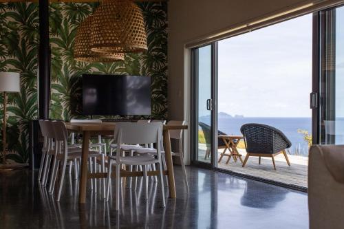 a dining room with a table and chairs with a view of the ocean at Oceanview Cottage Tutukaka Coast in Tutukaka