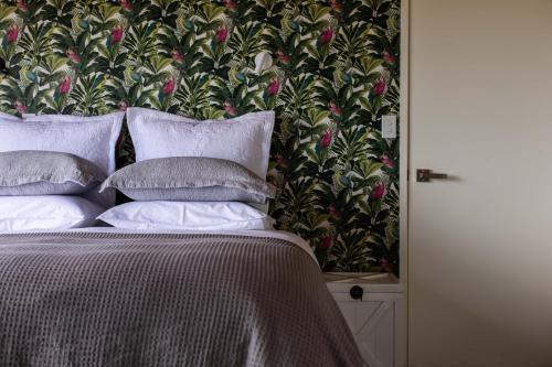a bed with white pillows and a floral wallpaper at Oceanview Cottage Tutukaka Coast in Tutukaka