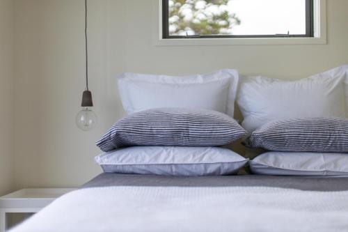 a pile of pillows sitting on top of a bed at Oceanview Cottage Tutukaka Coast in Tutukaka