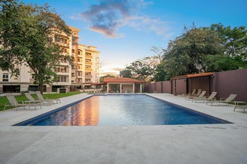 a swimming pool with chairs and a building at ✰Upscale 3Bdr condo✰ Incredible amenities ✰Fast wifi in Tamarindo