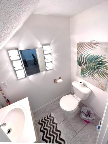 a bathroom with a toilet and a sink and two windows at The Ultimate Beach Getaway in Cape Canaveral