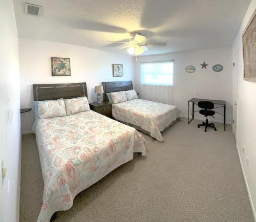 a bedroom with two beds and a table with a fan at The Ultimate Beach Getaway in Cape Canaveral