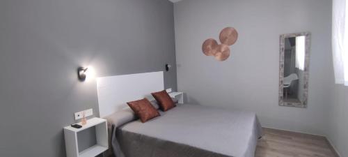 a white bedroom with a bed and a mirror at Apartamentos Las trece llaves Jacuzzi bajo reserva in Merida