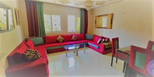 a living room with a red couch and a table at Appartement Haut Standing Petit Déjeuner INCLUS in Tangier