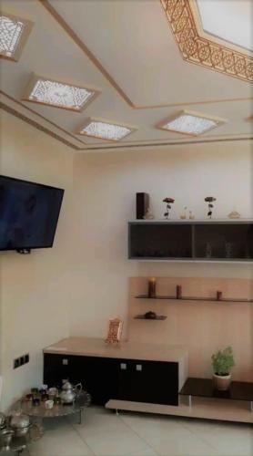 a living room with a table and a tv on the ceiling at Appartement Haut Standing Petit Déjeuner INCLUS in Tangier
