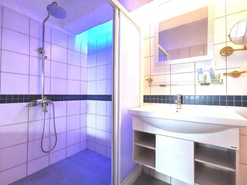baño púrpura con lavabo y ducha en La Maison B&B en Eluan