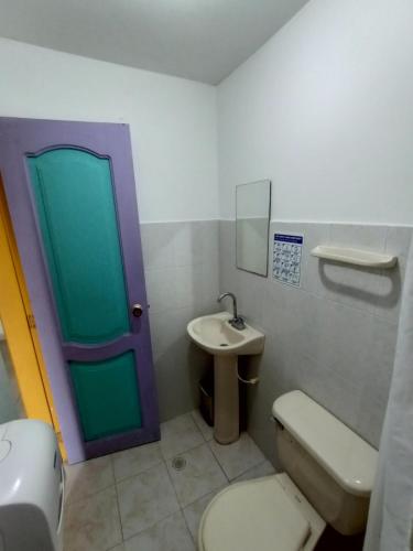 baño con aseo, lavabo y puerta en Hotel Brisas De Neguanje, en Santa Marta