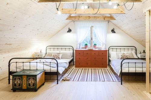 two beds in a attic bedroom with a wooden ceiling at Štvrtá voda - Chata so slovenským srdcom in Liptovský Ján