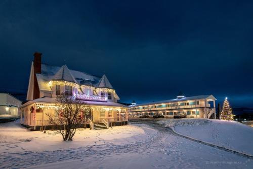 un complexe dans la neige la nuit avec un sapin de Noël dans l'établissement Hotel Plante, à Gaspé