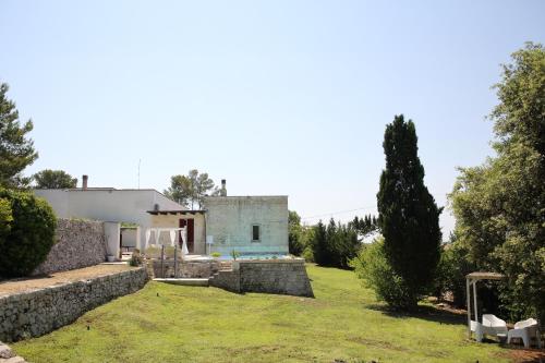 a house with a stone wall and a yard at Masseria Luci in Maglie