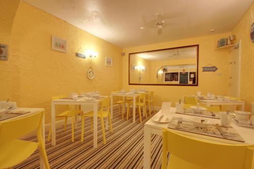 a restaurant with white tables and yellow chairs at The Rosslyn in Paignton