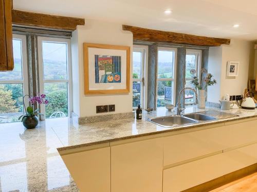 a kitchen with a sink and some windows at Woodlea Cottage in Huddersfield