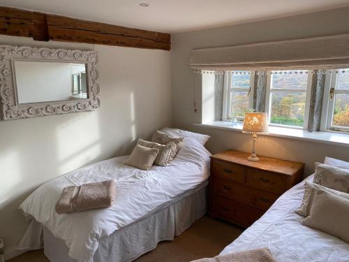 a bedroom with two beds and a mirror and windows at Woodlea Cottage in Huddersfield