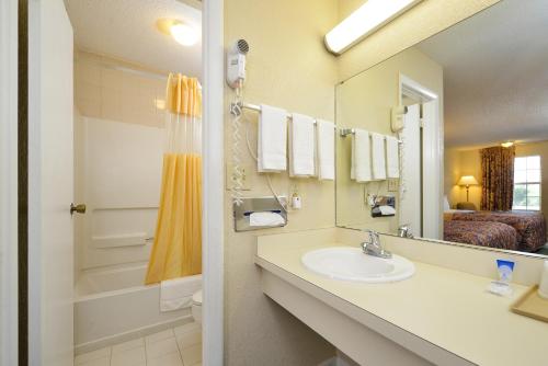 a bathroom with a sink and a mirror and a bed at Americas Best Value Inn-Winnsboro in Winnsboro