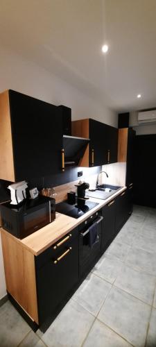 a kitchen with black cabinets and a counter top at Nez sur la croisette. in Dinant