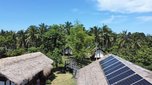a group of houses with solar panels and palm trees at Binga Beach Palawan Glamping in San Miguel