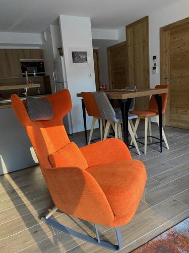 an orange chair in a living room with a table at LE DOUX MELEZE in Saint-Chaffrey