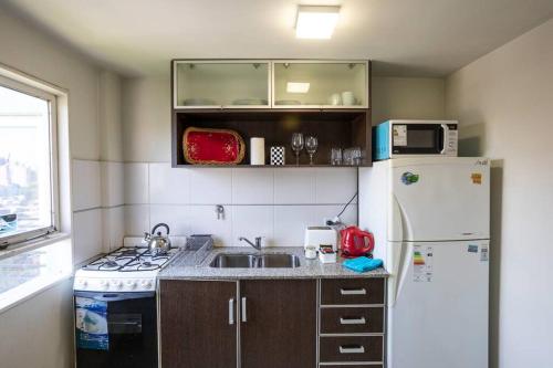 a kitchen with a white refrigerator and a sink at Best Parque - Pileta y Cochera - Solo autos in San Miguel de Tucumán