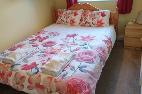 a bed with a floral bedspread and towels on it at Lovely Cosy Apartment near Water Parks in South Cerney