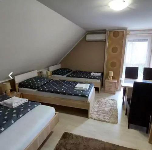 a bedroom with two beds and a desk and a table at Fáraó vendégház in Zalaegerszeg
