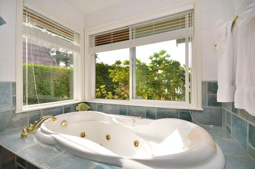 een badkamer met een wit bad en 2 ramen bij Columbia Beach House in Parksville