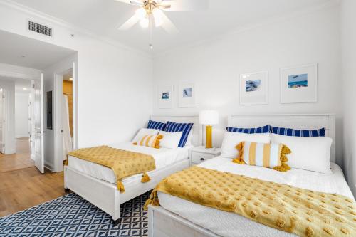 Duas camas num quarto branco com almofadas azuis e amarelas em Indigo West 1101 em Perdido Key