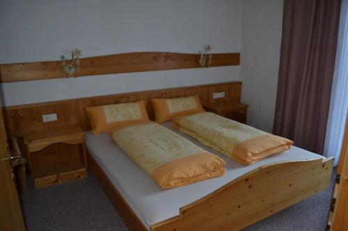 1 dormitorio con 1 cama de madera y 2 almohadas en Landhaus Leutaschtal, en Leutasch