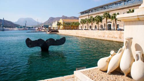 a sculpture in the water next to a building at CARTAGENAFLATS, Apartamentos San Francisco in Cartagena