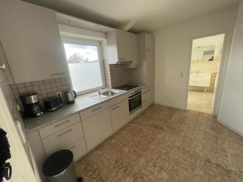 a kitchen with white cabinets and a sink and a window at Zimmervermietung Am Airport in Bremen