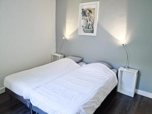 um quarto com uma cama com lençóis brancos e duas luzes em Les Arènes, 1 à 6 personnes en centre ville em Nîmes