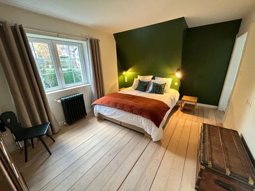 1 dormitorio con cama y pared verde en Le Hêtre Rouge Charme & Spa, en Barr