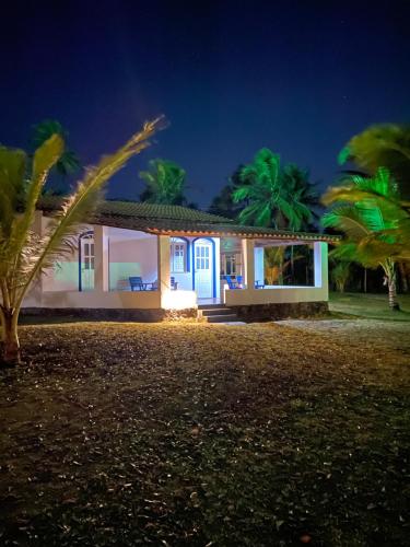 una casa con puertas azules y palmeras por la noche en Alma Tropical Resort, en Vera Cruz de Itaparica