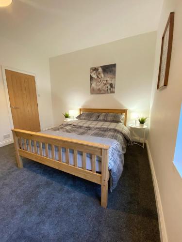 A spacious & modern 3-bed home في بلاكبيرن: غرفة نوم بسرير خشبي في غرفة