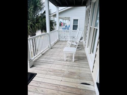 un porche con una silla blanca en una casa en Le Tournesol, en Holden Beach