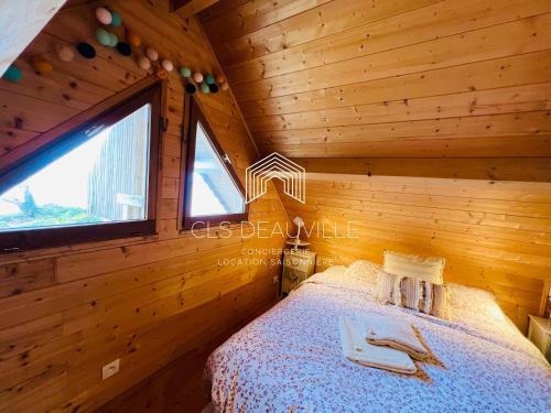 a bedroom in a log cabin with a bed and a window at Chalet Bord de Mer CLS Deauville in Cricquebœuf