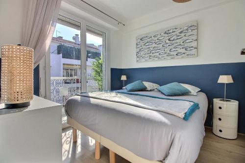 une chambre avec un lit aux murs bleus et une fenêtre dans l'établissement CENTRAL CANNES, à Cannes