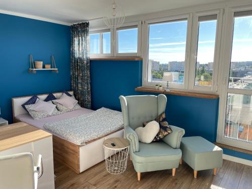 a bedroom with blue walls and a bed and a chair at Apartament z pięknym widokiem na zachodni Szczecin in Szczecin