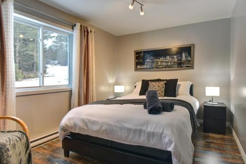 a bedroom with a large bed and a window at Sheldon Enchanting on Lake Cottage with Jacuzzi in Rivière-Rouge