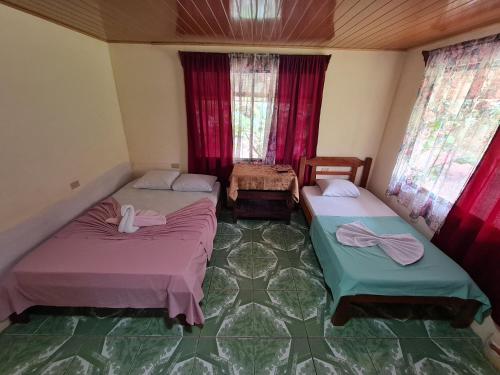 two beds in a room with red curtains at Casa Tucan in Drake