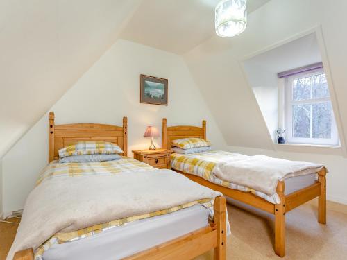 two twin beds in a room with a window at Curin Cottage Strathconon in Contin